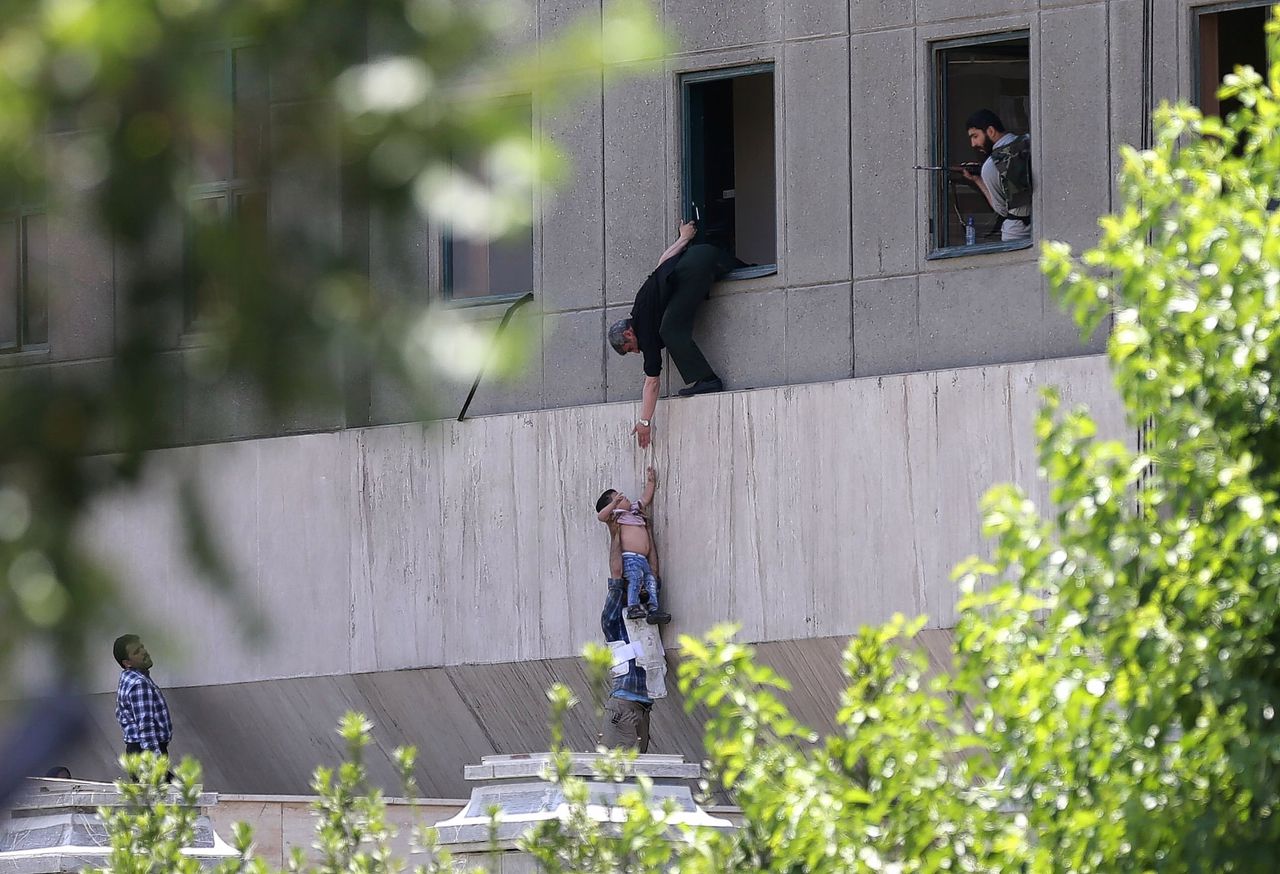 Agenten redden een kind uit het parlementsgebouw in Teheran, tijdens de aanval op het gebouw.