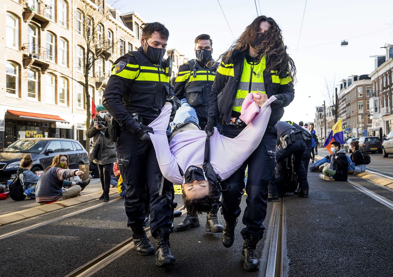 Een klimaatactivist van Extinction Rebellion wordt in Amsterdam weggedragen door de politie.