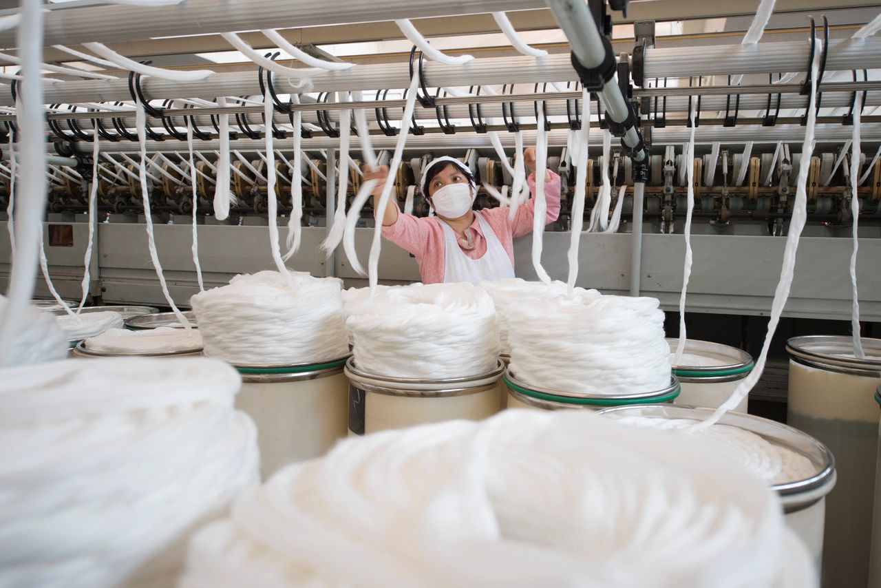 Een werknemer met een mondkapje aan het werk in een Chinese textielfabriek in Haia, in de provincie Jiangsu.