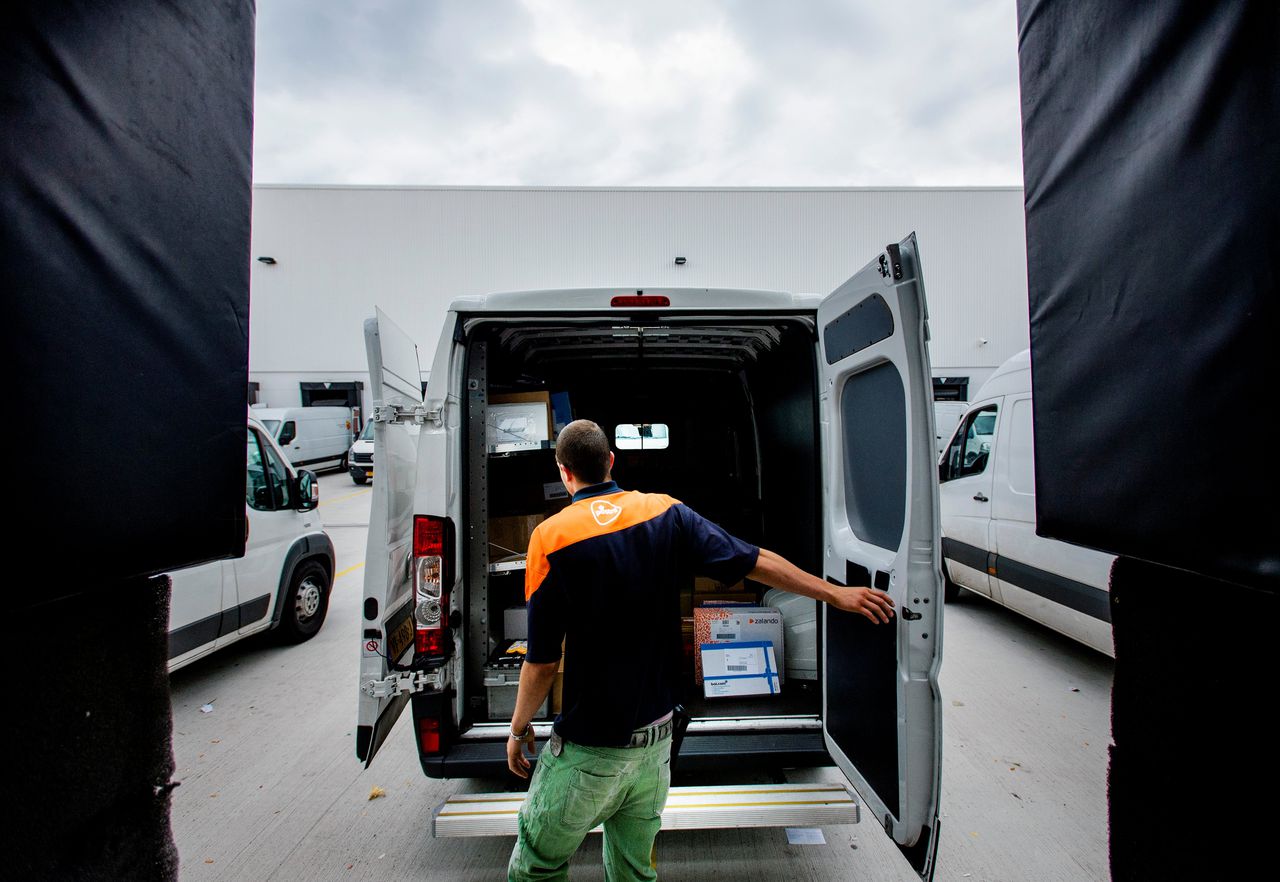 Een medewerker verplaatst postpakketten in een sorteercentrum van PostNL.