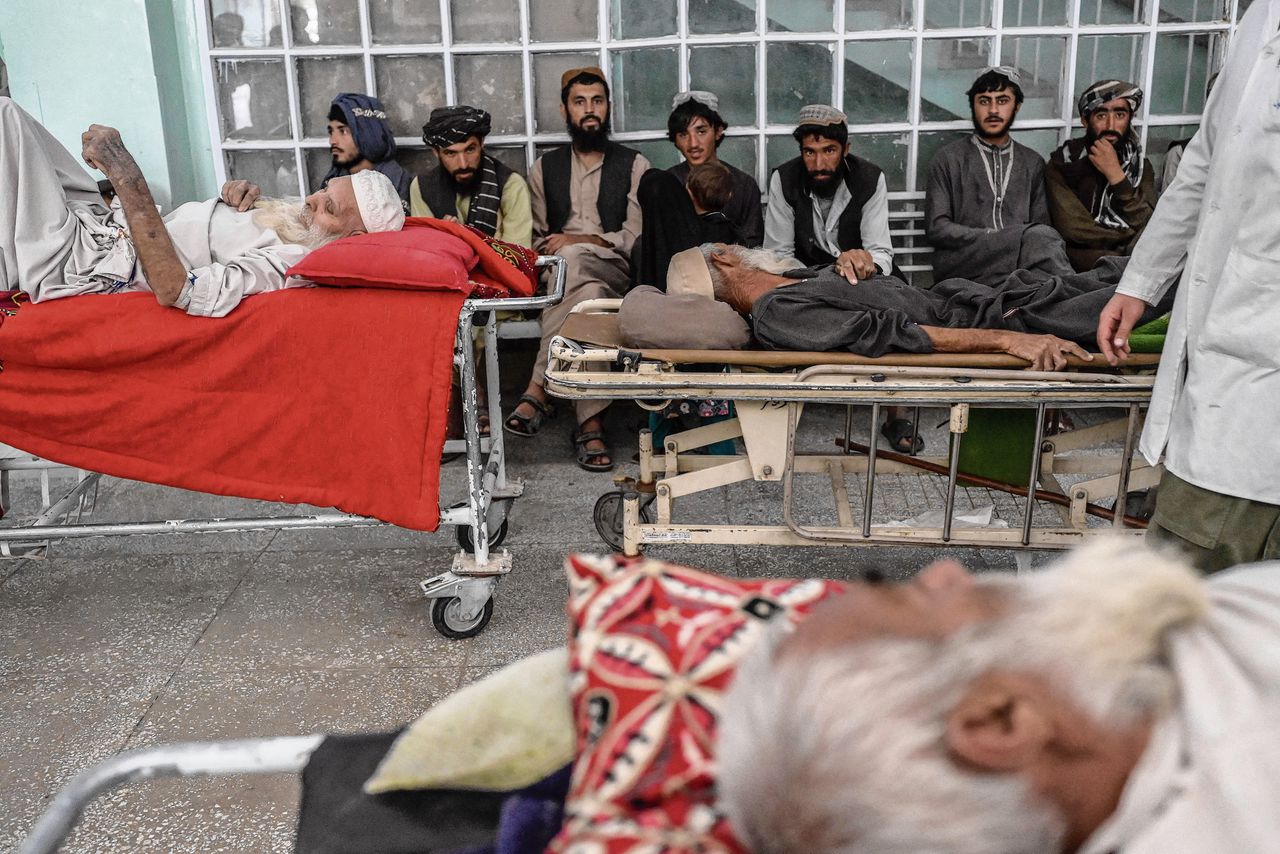 Patiënten wachten maandag op medische zorg in een gang van het Mirwais ziekenhuis in Kandahar (boven), een kind wordt er behandeld (onder).