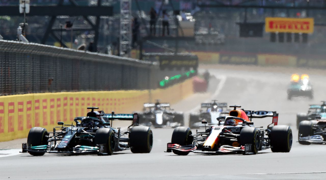 Lewis Hamilton (links) en Max Verstappen gaan naast elkaar de bocht in, in de openingsronde.