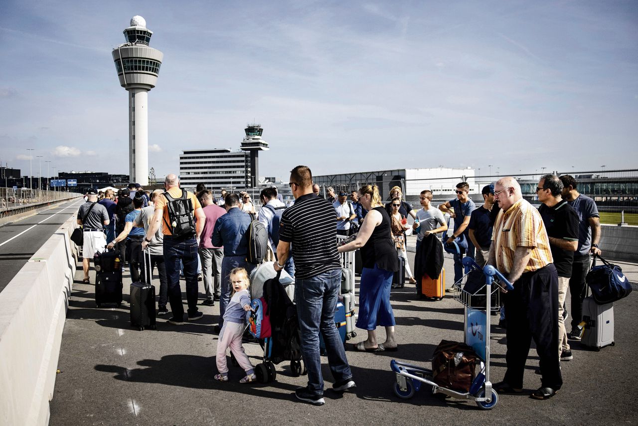 Reizigers in de rij op luchthaven Schiphol. Het is druk door de krappe bezetting bij de security.
