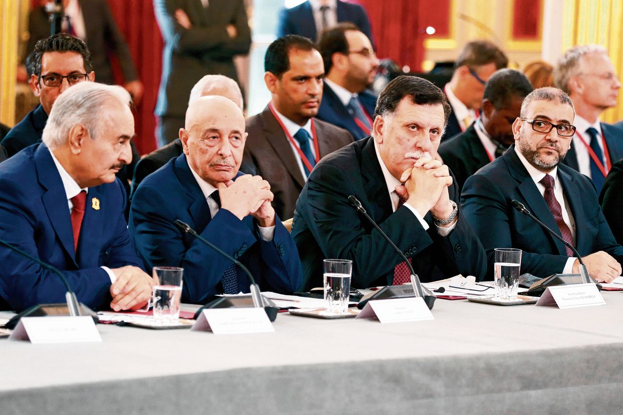 De sterke man uit het oosten van Libië, Khalifa Haftar (links), en zijn rivaal, premier Fayez Sarraj (tweede van rechts) op de conferentie van dinsdag in Parijs.