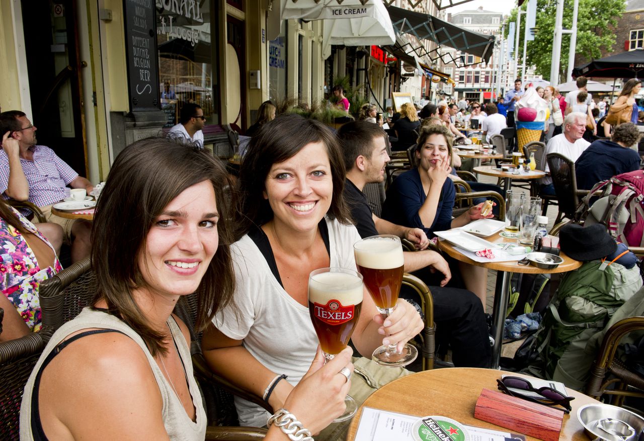 AMSTERDAM – Twee vriendinnen proosten op een terras aan de Nieuwmarkt. Foto ANP/Marcel Antonisse