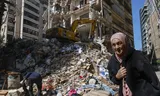 Een vrouw loopt langs een verwoeste woning na een Israëlische luchtaanval op de wijk Ain Mreisseh in Beiroet. 