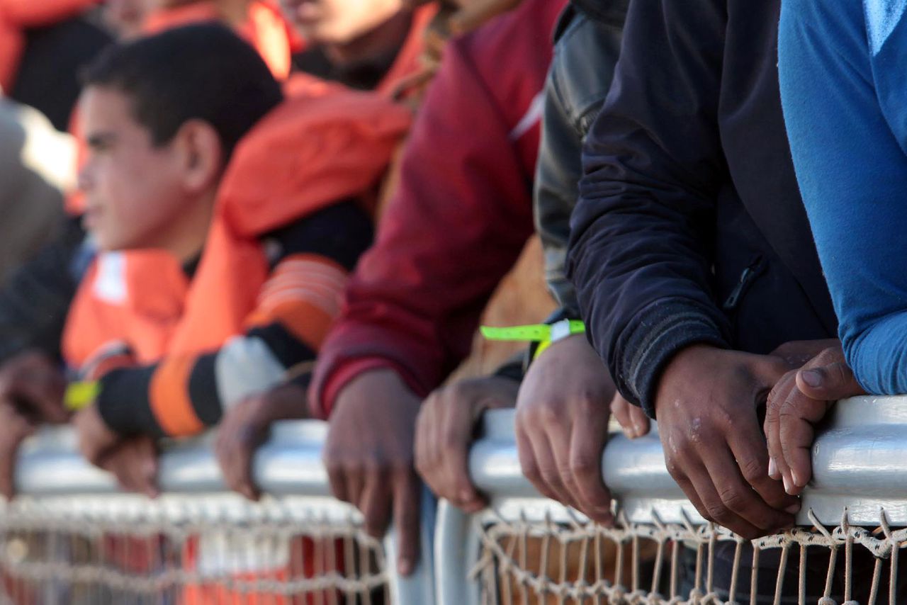 Migranten en vluchtelingen wachten om een reddingsboot te verlaten in de haven van Sicilië.