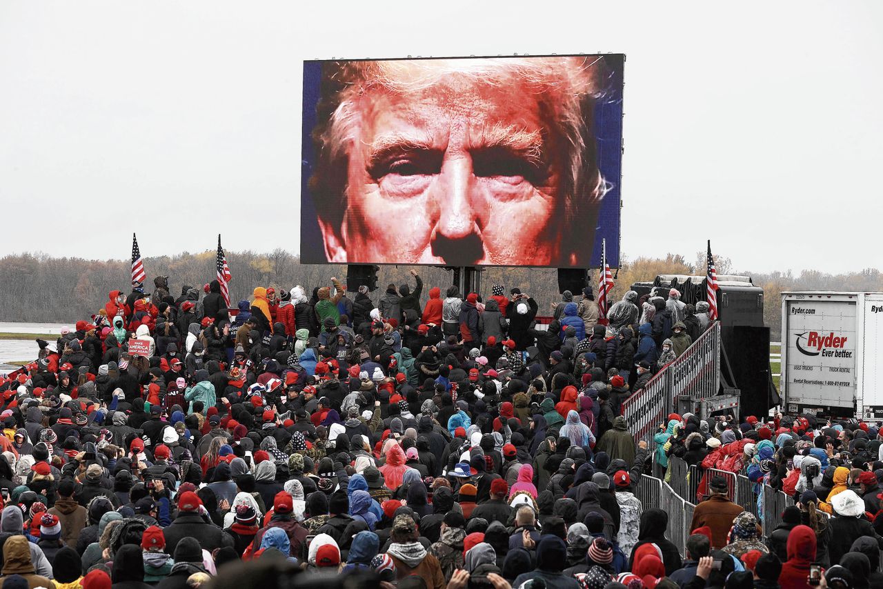Aanhangers van de Amerikaanse president Trump wachten in de stromende regen op het vliegveld van Lansing, Michigan op de aankomst van hun presidentskandidaat.