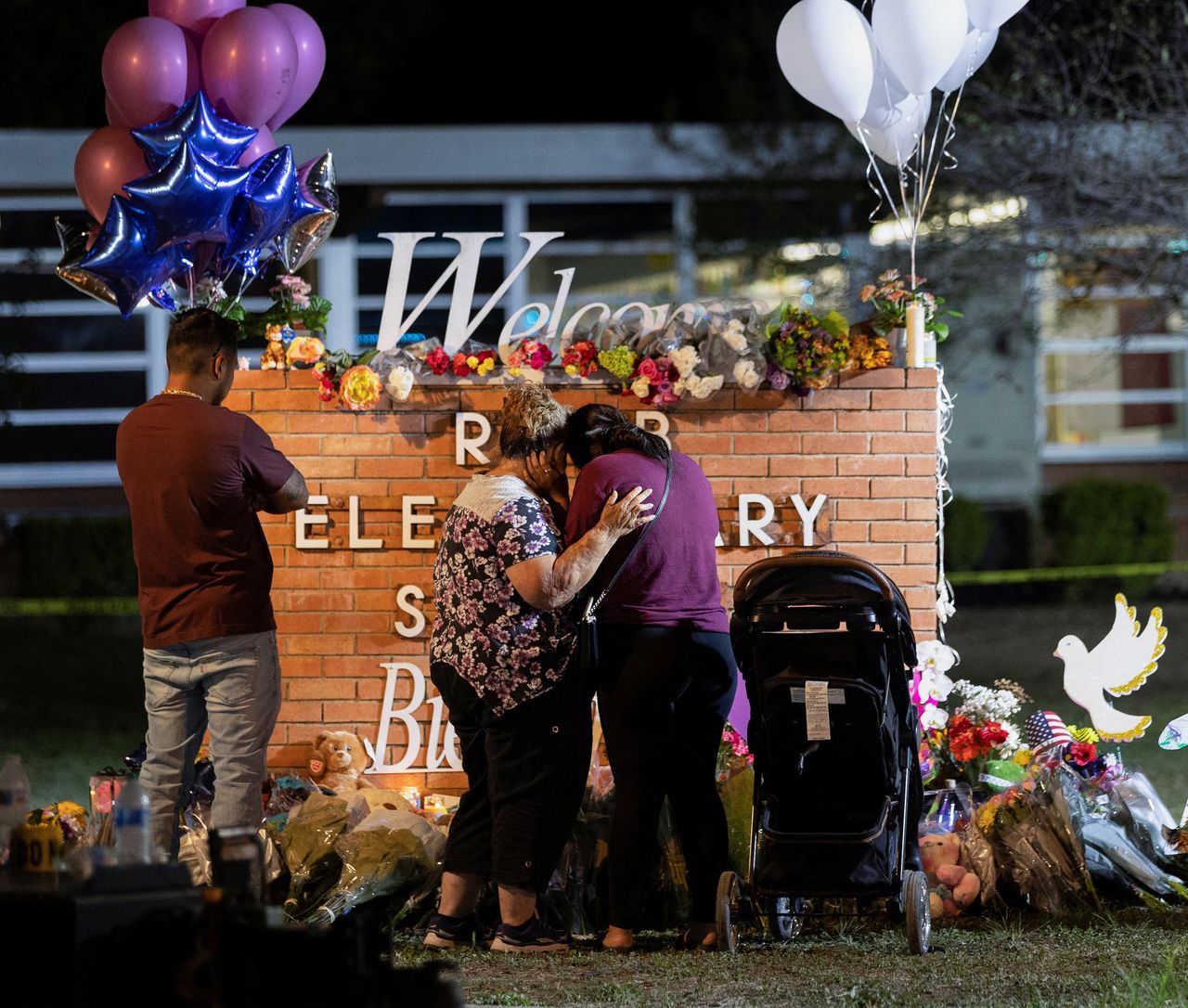 Mensen troosten elkaar bij de gedenkplaats voor de 21 slachtoffers die een 18-jarige schutter vorige maand maakte op een basisschool in Uvalde, Texas.