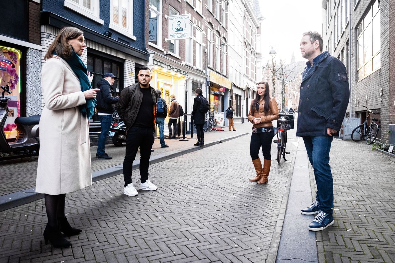 Stieneke van der Graaf spreekt in Den Haag met ex-drugsgebruikers Sergej Chatsjatarjan, Kicky Heuseveldt en Patrick de Jong (v.l.n.r.). Op de achtergrond staan mensen in de rij voor een coffeeshop.