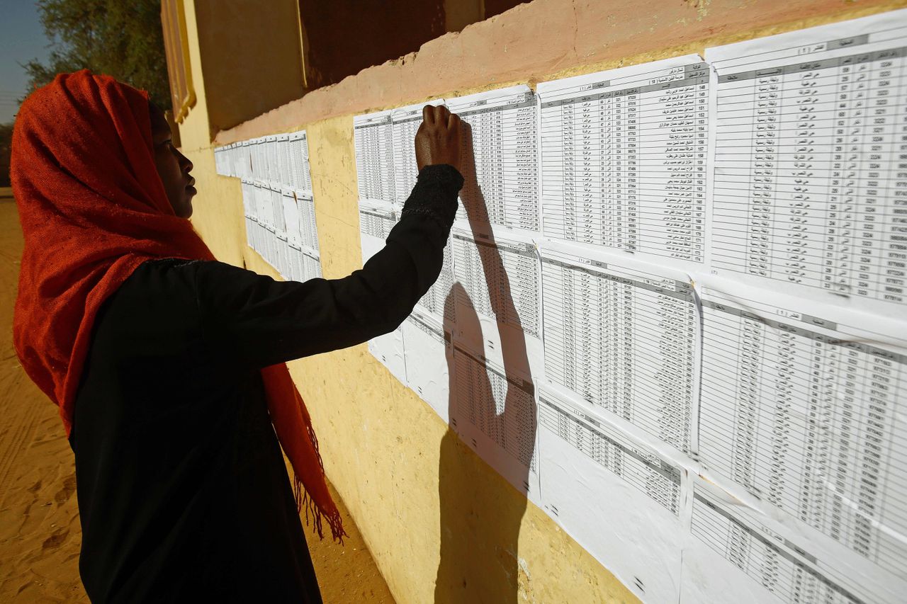Een vrouw checkt of haar naam op de lijst met kiesgerechtigden staat bij een stembureau in het vluchtelingenkamp Abu Shouq.