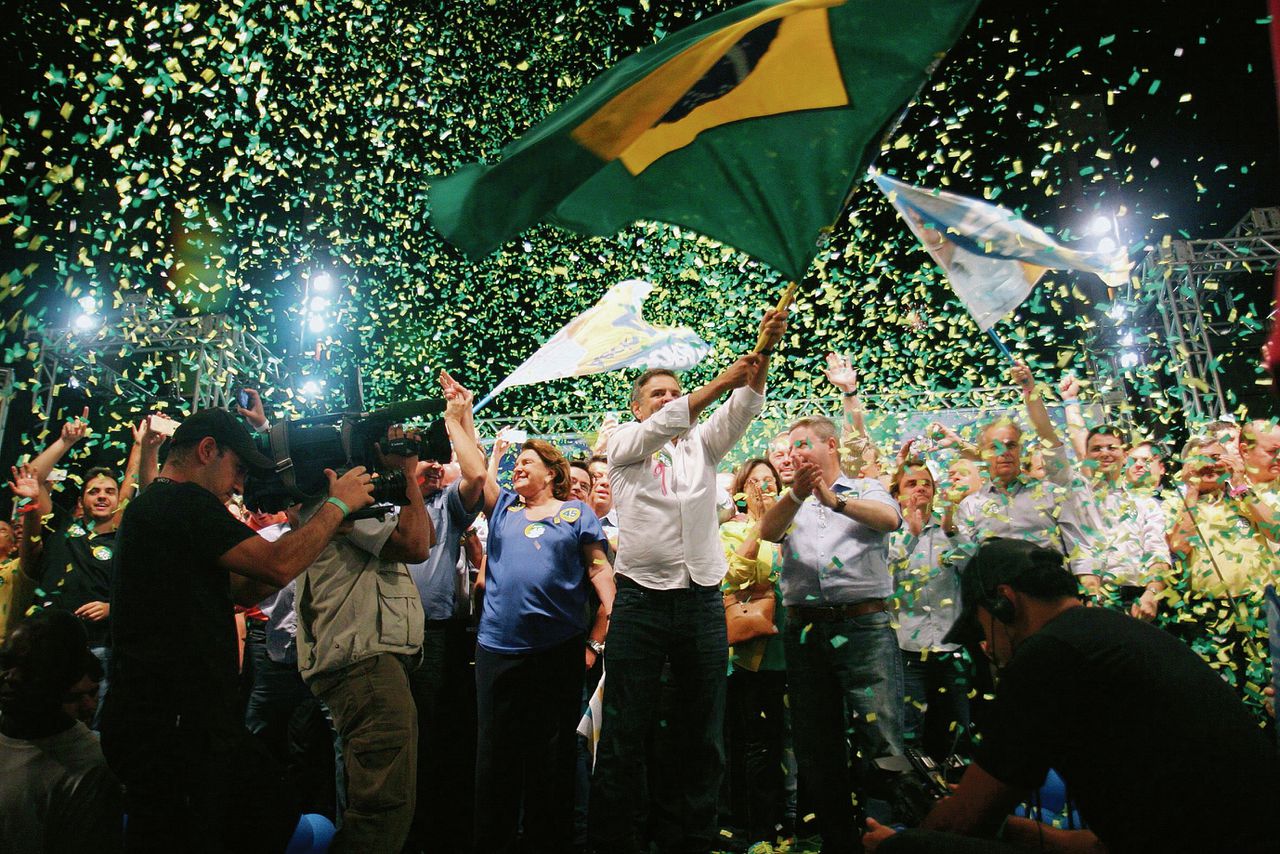 De centrumrechtse presidentskandidaat Aécio Neves zwaait met de Braziliaanse vlag, tijdens de campagne. Het verschil tussen hem en Rousseff valt feitelijk mee: ook hij zal de sociale programma’s niet afschaffen.
