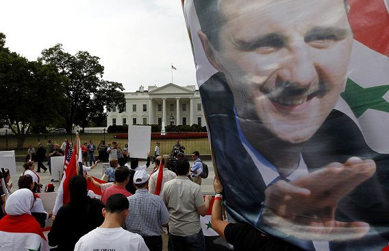 Een demonstrant houdt een grote afbeelding van president Assad omhoog. Tegenstanders van een militaire interventie in Syrië protesteren voor het Witte Huis.