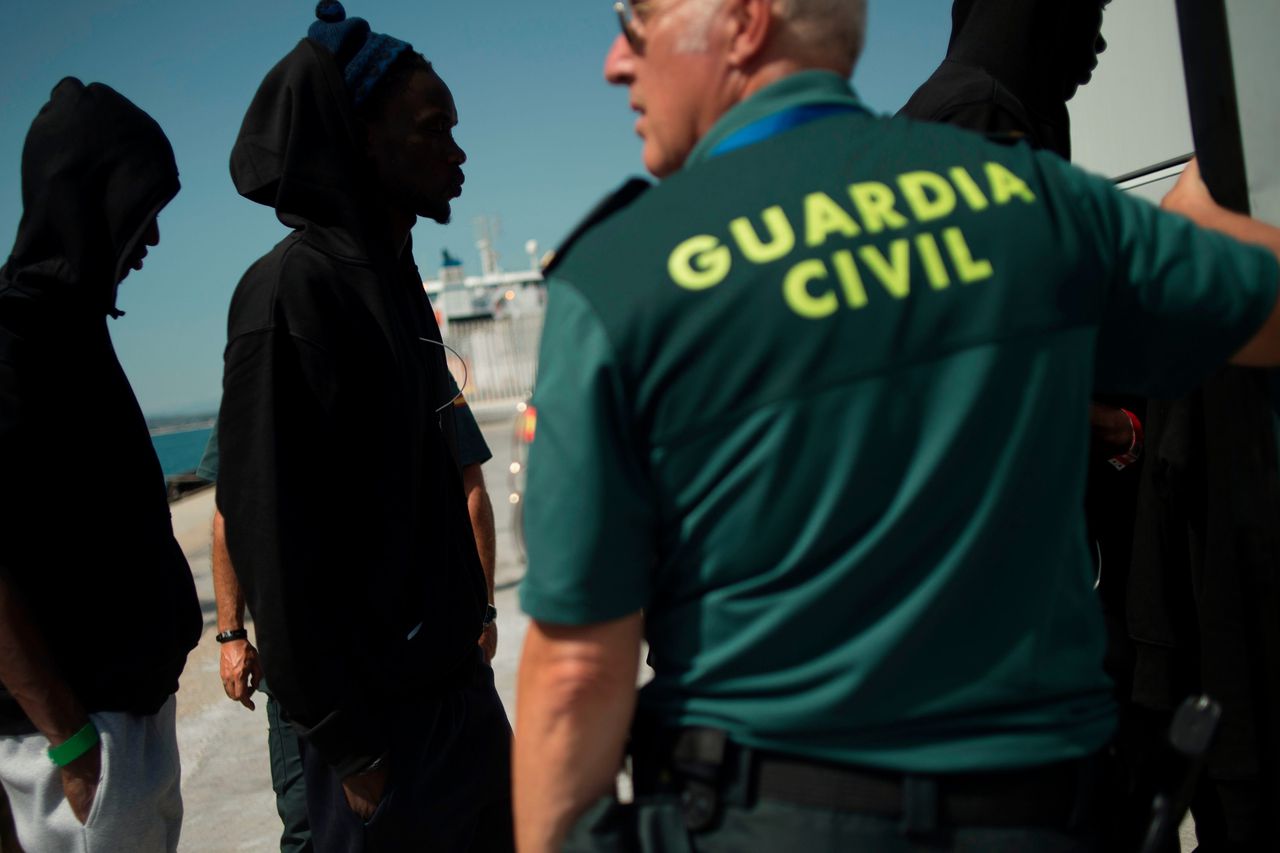 Leden van de Spaanse Guardia Civil kijken toe terwijl migranten van boord komen van een schip van de kustwacht, op 21 juli dit jaar in de havenstad Algeciras.
