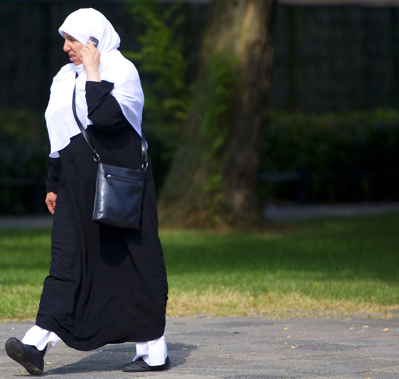 Moslima loopt met telefoon over straat in Utrecht. Ouders van radicaliserende jongeren kunnen vanaf vandaag terecht bij een hulplijn van het SMN.