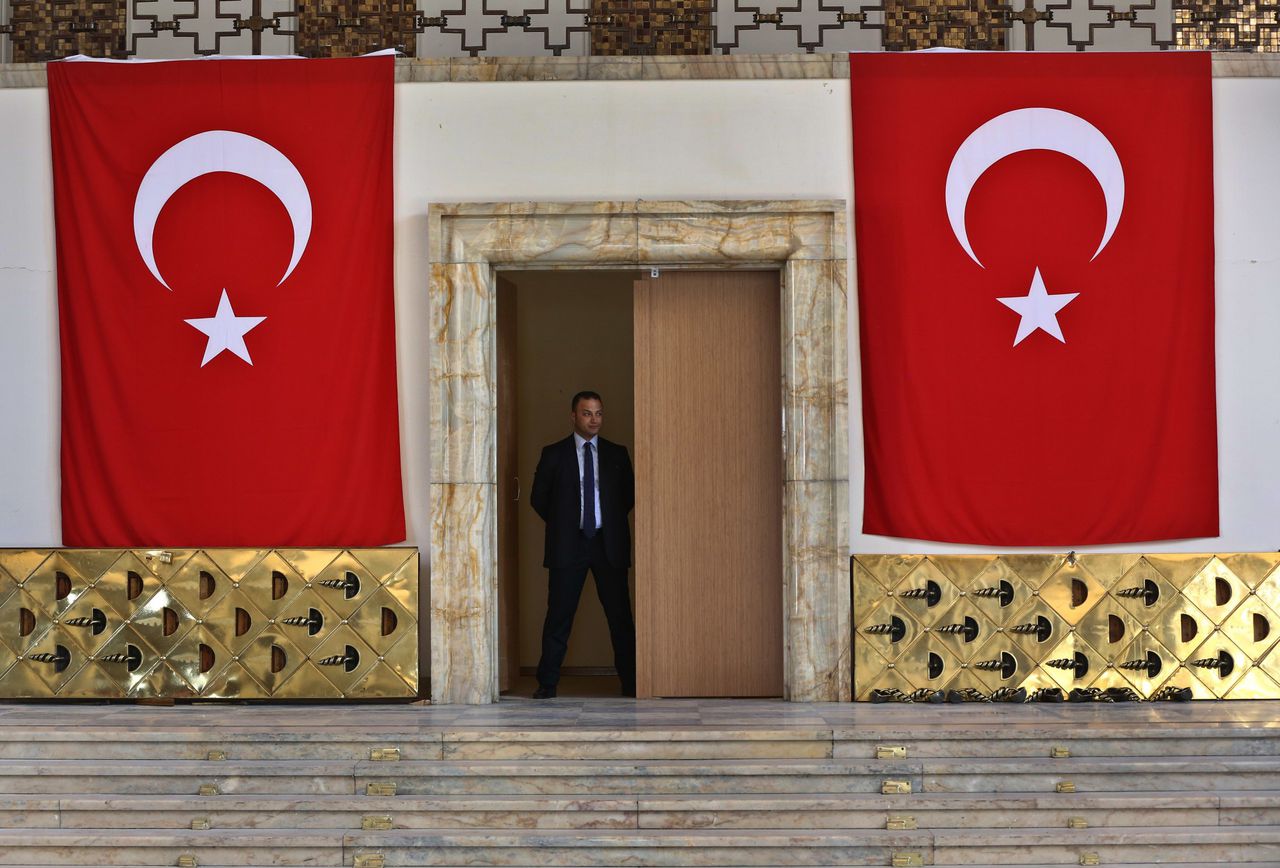 Een bewaker staat in de deuropening van het Turkse parlement. Op de grond liggen de koperen deuren die werden vernield tijdens de couppoging.