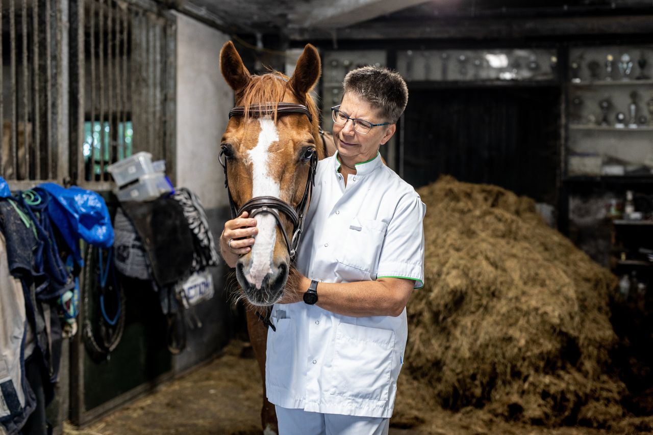 Bianca Vet met haar röntgenlaborantkleding naast haar paard Reflex.