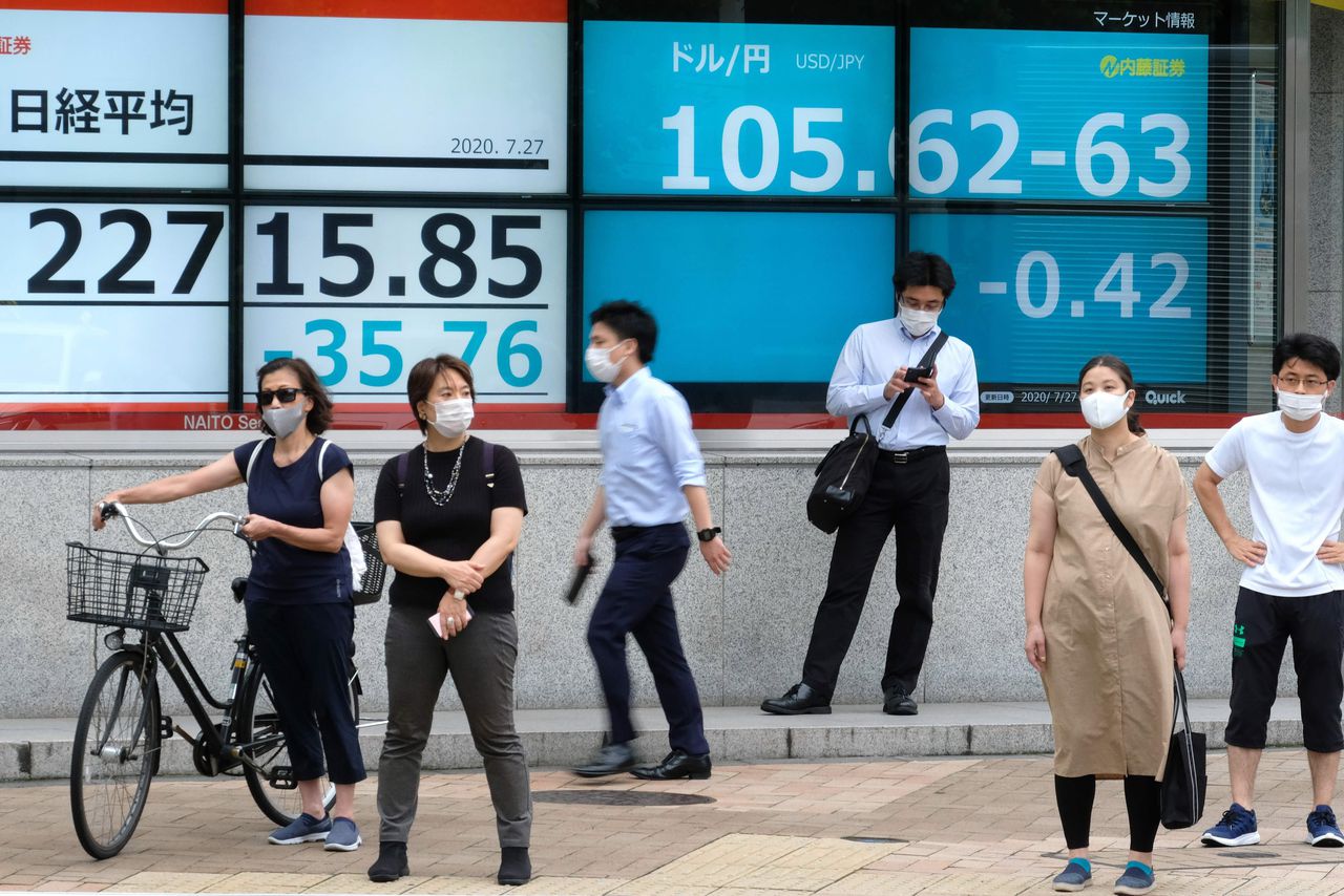 Voetgangers in Tokio staan voor een scherm met de wisselkoersen van de Amerikaanse dollar en de Japanse yen.
