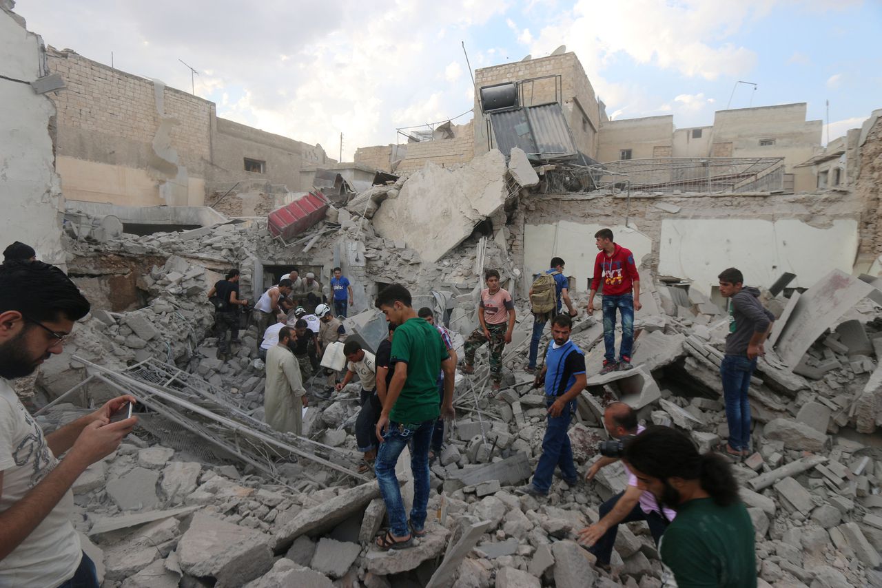 Mensen zoeken naar overlevenden onder het puin van een getroffen gebouw in Aleppo.