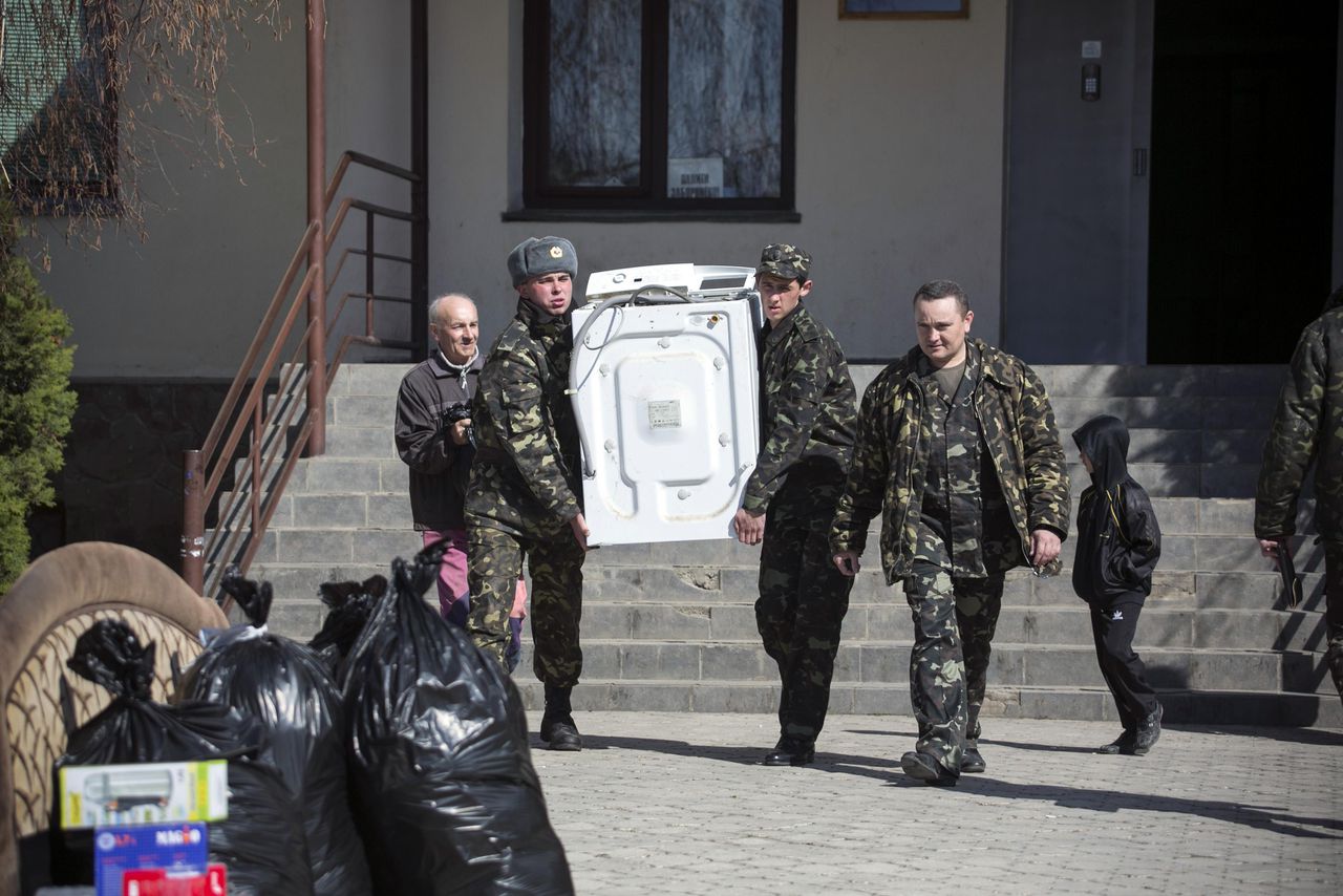 Oekraïense militairen dragen een wasmachine naar een busje. De soldaten verlaten de basis in het dorp Lyumbimovka, nabij Sebastopol nu de Krim geannexeerd is door Rusland.