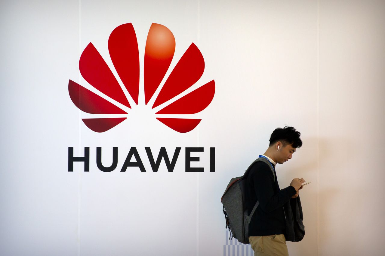 Een voorbijganger checkt zijn smartphone bij een logo van het Chinese technologieconcern Huawei n Beijing, in oktober 2019.