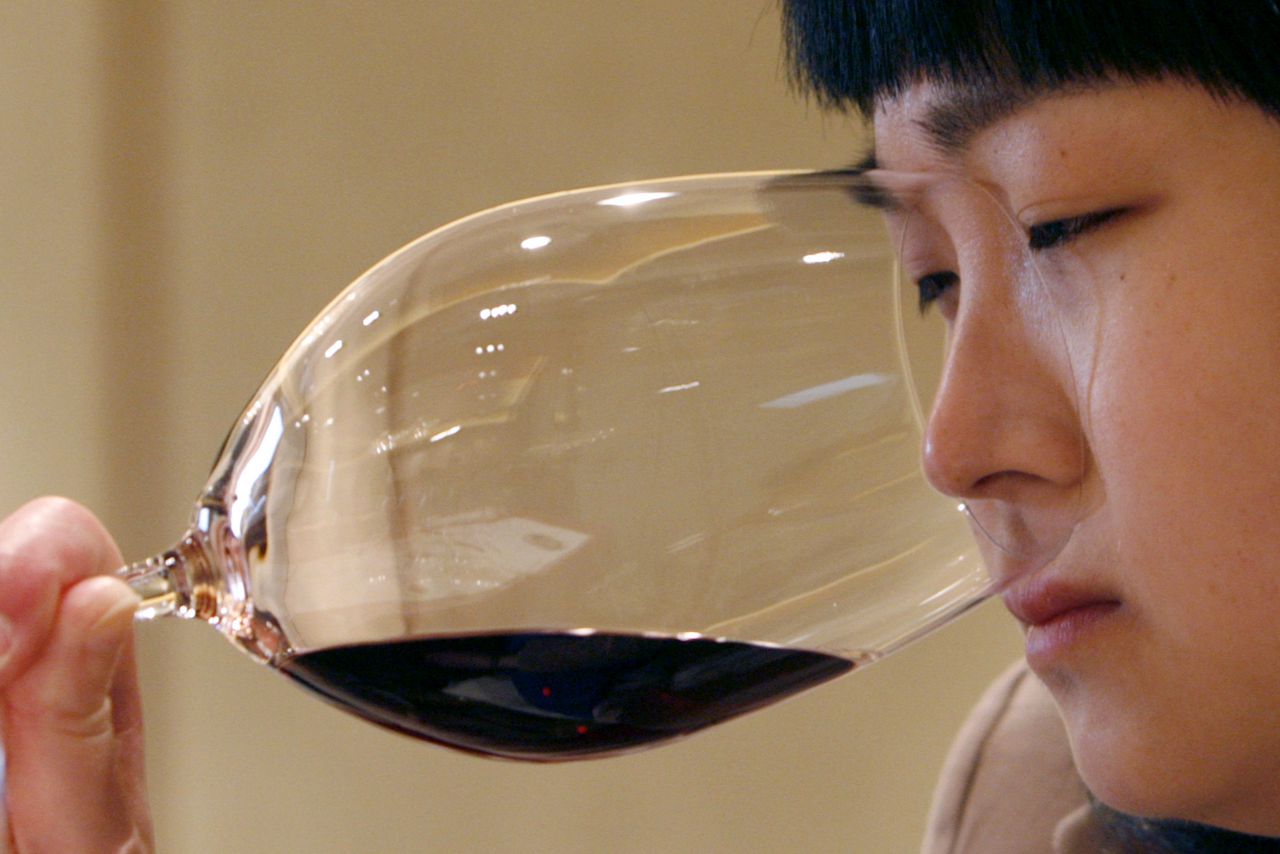 Wijn proeven in Peking (Foto Reuters) A woman smells red wine during the Chateau Haut Brion wine-tasting event in Beijing April 18, 2007. Beijing is prising open a wine industry growing some 11 to 12 percent annually as increasingly wealthy Chinese opt for more expensive liquor, but steady competition is eroding margins. REUTERS/Claro Cortes IV (CHINA)