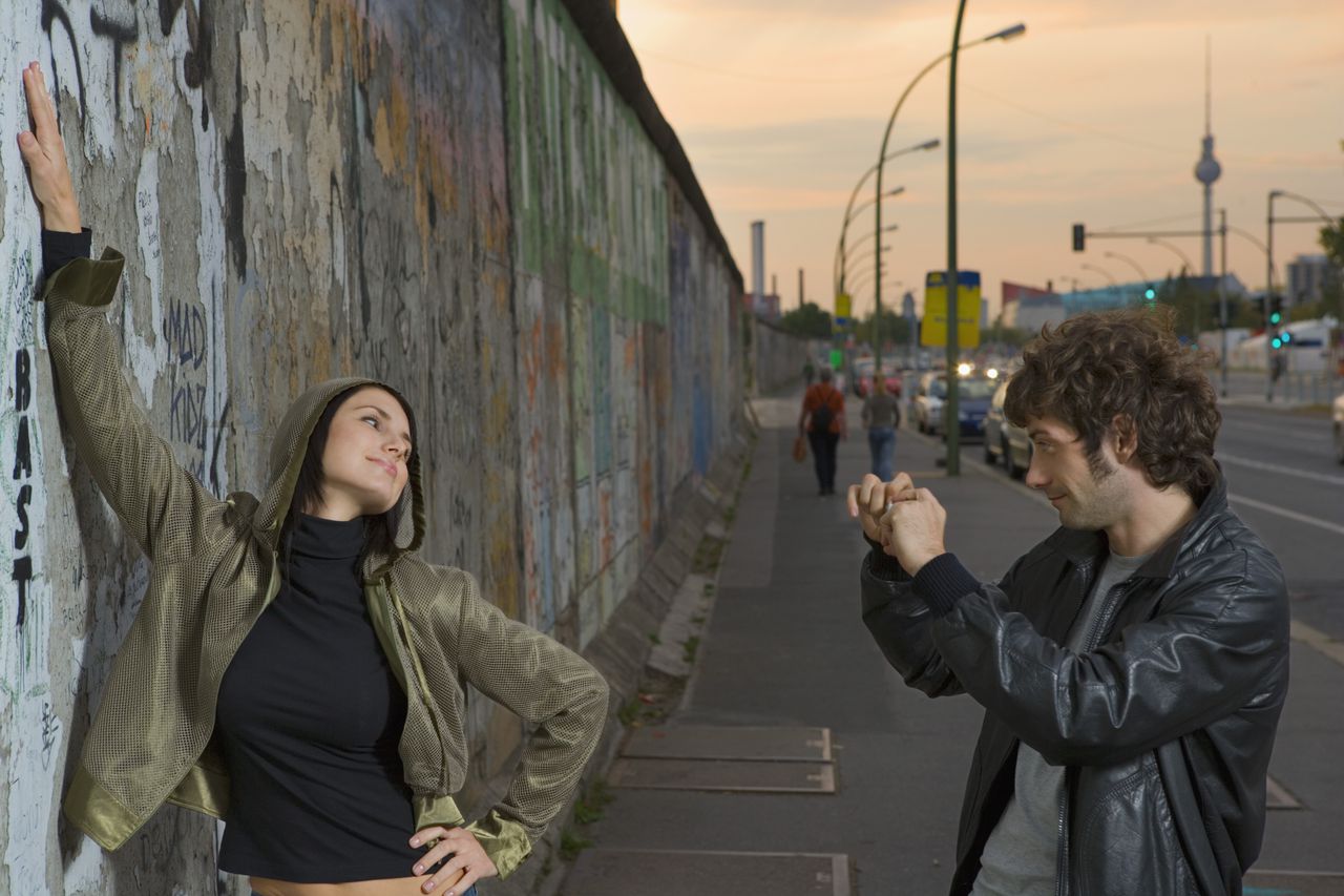 Berlin, Germany --- Man Photographing Girlfriend by Berlin Wall --- Image by © Roy Botterell/Corbis