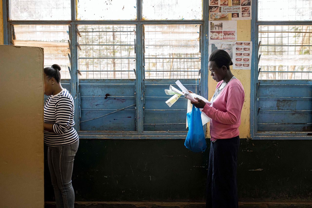 Een Keniaanse vrouw bekijkt haar stembiljet in de rij voor het stemhokje.