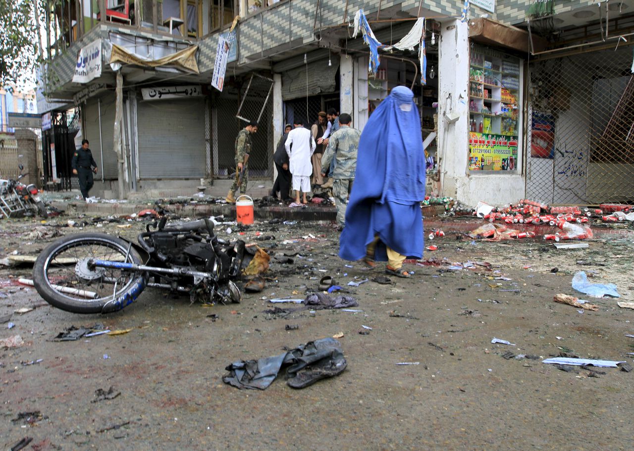 Een Afghaanse vrouw loopt langs de plek waar vandaag een zelfmoordaanslag plaatsvond in Jalalabad. Meer dan 30 mensen werden gedood.