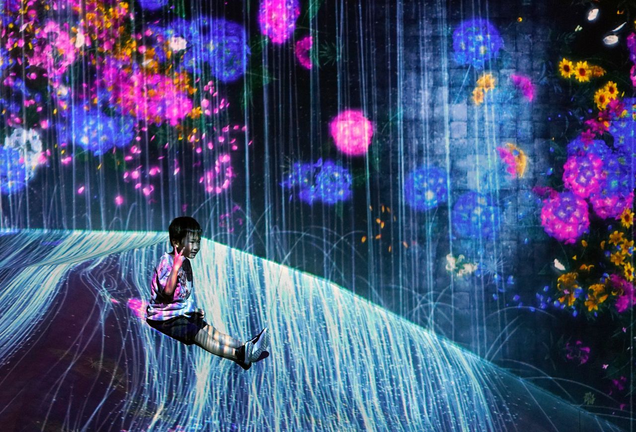 Een jongen zit in het 10.000 vierkante meter grote digitale kunstwerk ‘teamLab Borderless’. Een Digital Art Museum van teamLab in Tokio in 2019.