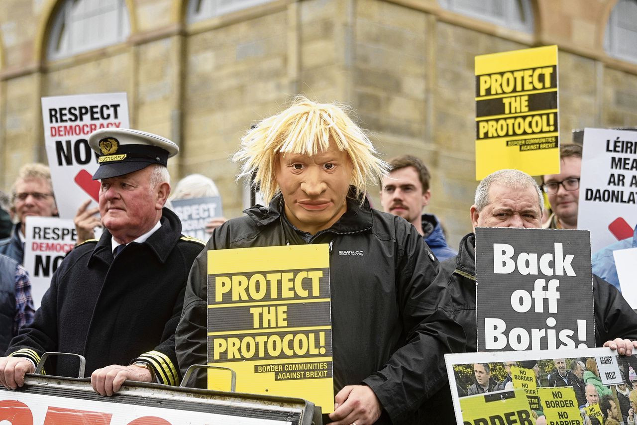 Een betoger met een masker van de Britse premier Boris Johnson wacht op diens aankomst in Noord-Ierland.