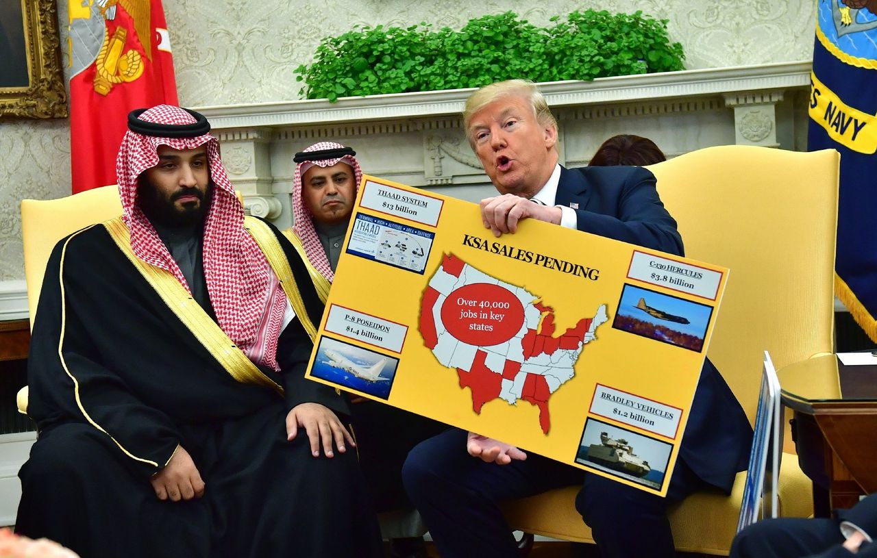 Donald J. Trump (R) houdt een bord vast waarop de verkoop van militaire apparatuur is afgebeeld, tijdens een ontmoeting met Mohammed bin Salman in het Witte Huis.