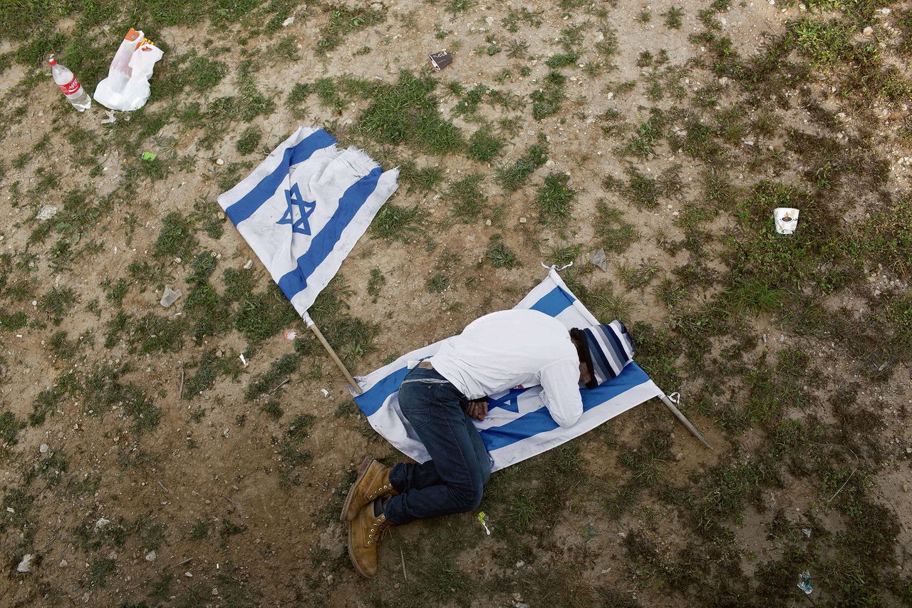 Een Israëlische jongen ligt op de vlag van zijn land tijdens een religieus volksfeest Foto AP