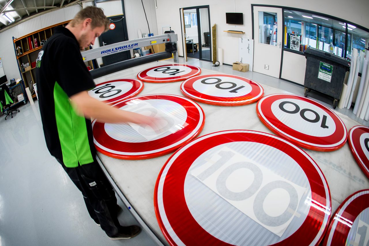 Bij Visser print & sign in Assen worden nieuwe verkeersborden voor de maximale snelheid 100 km per uur beplakt.