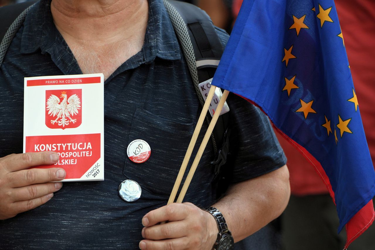 Een demonstrant houdt een exemplaar van de Poolse grondwet en een EU-vlag vast bij een protest.
