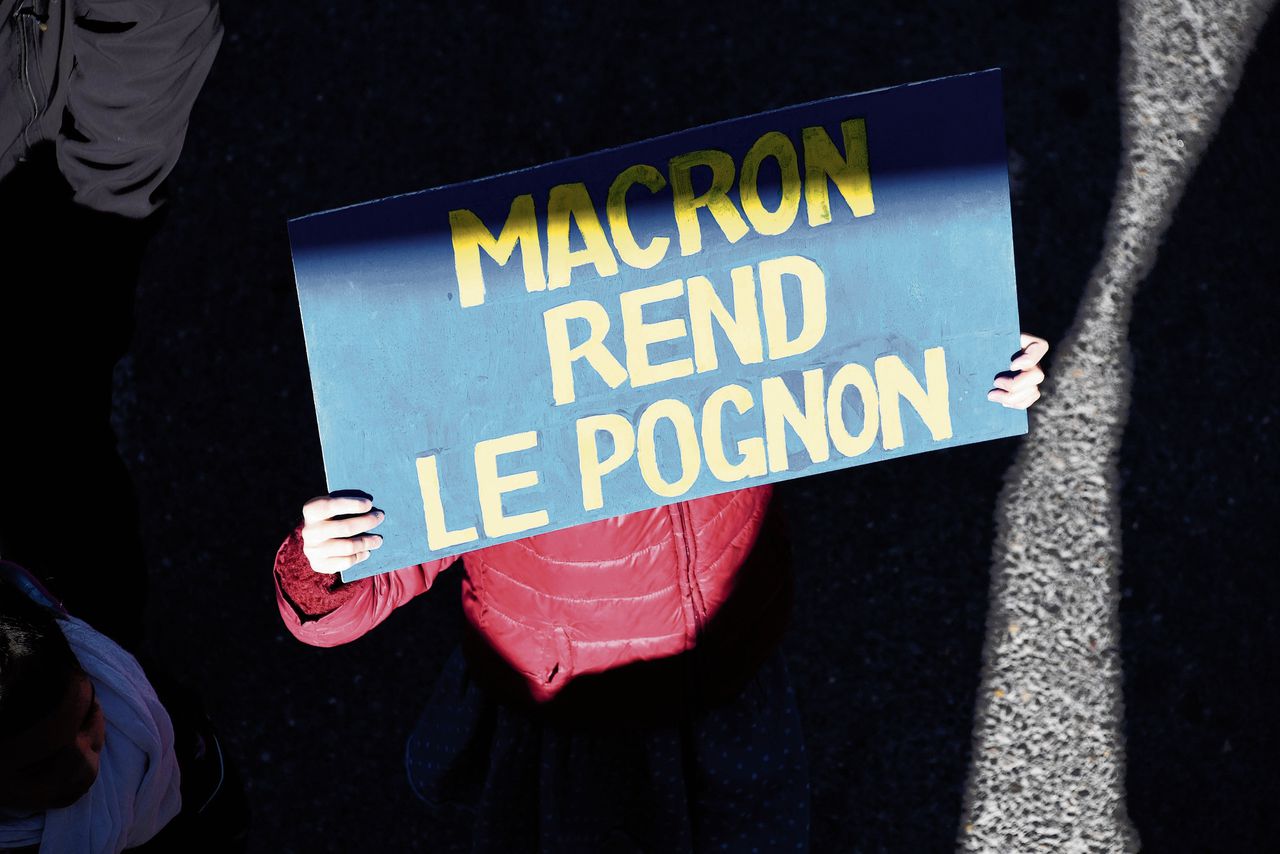 Een actievoerder met het bord ‘Macron, geeft het geld terug’.