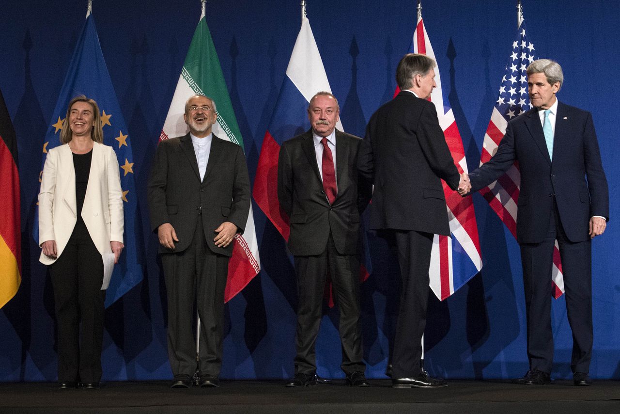 EU-buitenlandchef Federica Mogherini en de Iraanse minister van Buitenlandse Zaken Javad Zarifat kijken toe hoe de Britse minister van Buitenlandse Zaken Philip Hammond de hand schudt van zijn collega John Kerry, in Lausanne.