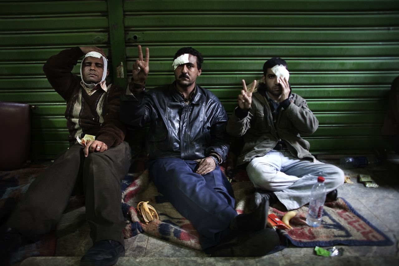 Egyptian anti-regime protesters wounded during clashes with government supporters flash victory signs as they rest after receiving medical treatment at a makeshift clinic at the Ibad al-Rahman mosque near the flashpoint Tahrir Square in Cairo on February 2, 2011. AFP PHOTO/MARCO LONGARI