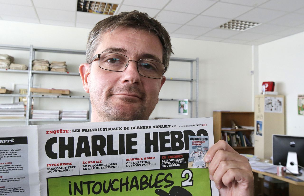 Bijgesneden foto van AP uit 2012 met hoofdredacteur 'Charb' van Charlie Hebdo. Hij houdt een uitgave van het weekblad omhoog waarop de profeet Mohammed te zien is.