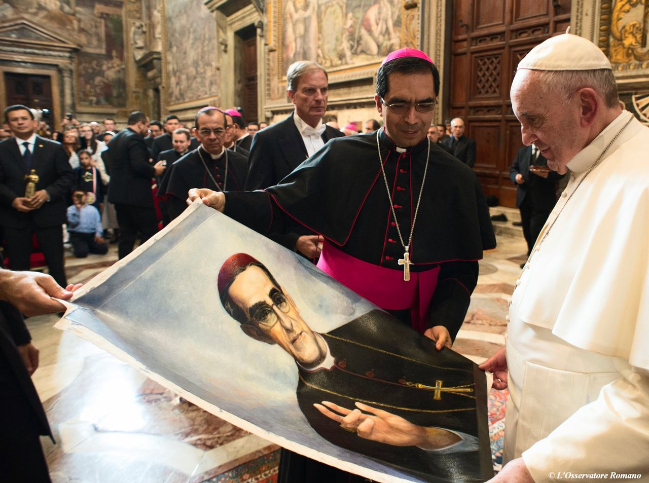 Tijdens een ontmoeting met Paus Franciscus in 2015 bieden pelgrims uit El Salvador hem een poster aan met de foto van aartbisschop Oscar Romero.