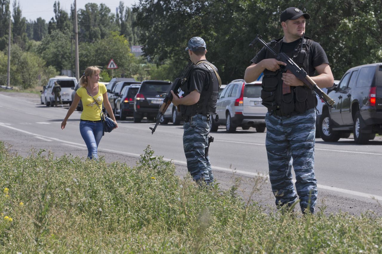 Pro-Russische rebellen staan bij het konvooi van de forensische experts.