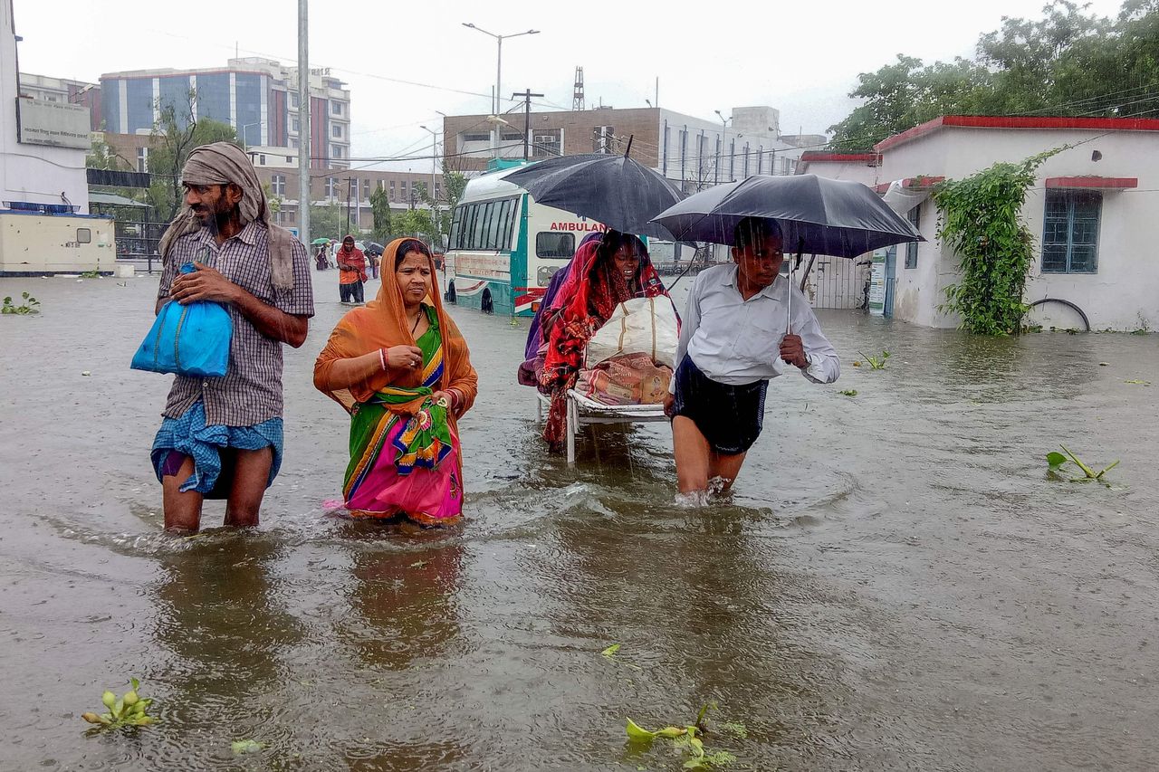 Patiënten waden zaterdag door het water op weg naar een ziekenhuis in de noordelijke Indiase staat Bihar.