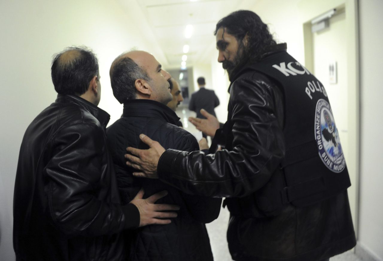 Oproerpolitie neemt de hoofdredacteur van Zaman (m) mee, nadat ze een inval heeft gedaan in het hoofdkantoor van de oppositiekrant.