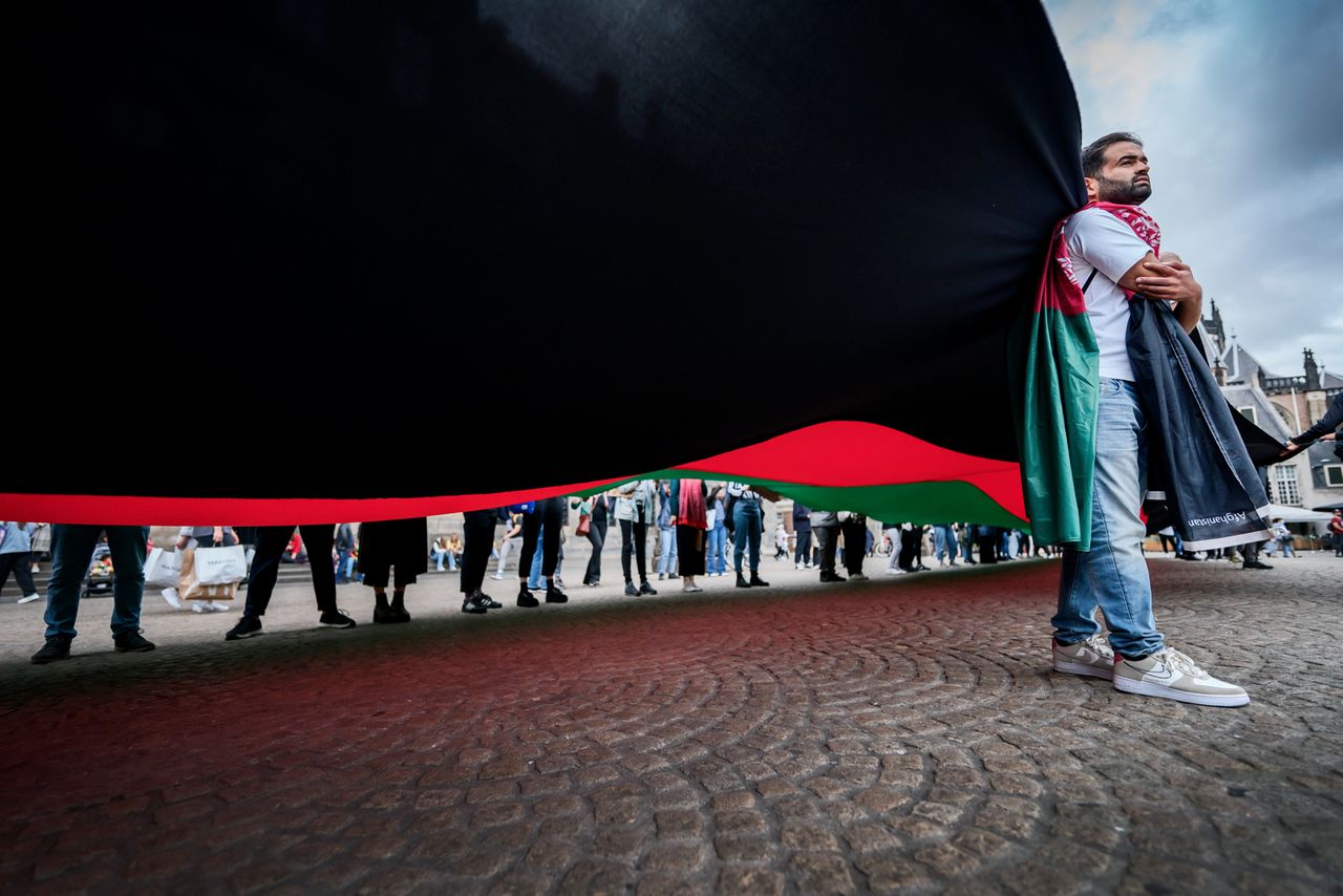 Er wordt een grote Afghaanse vlag gespannen over de Dam, tijdens de Afghanistandemonstratie.
