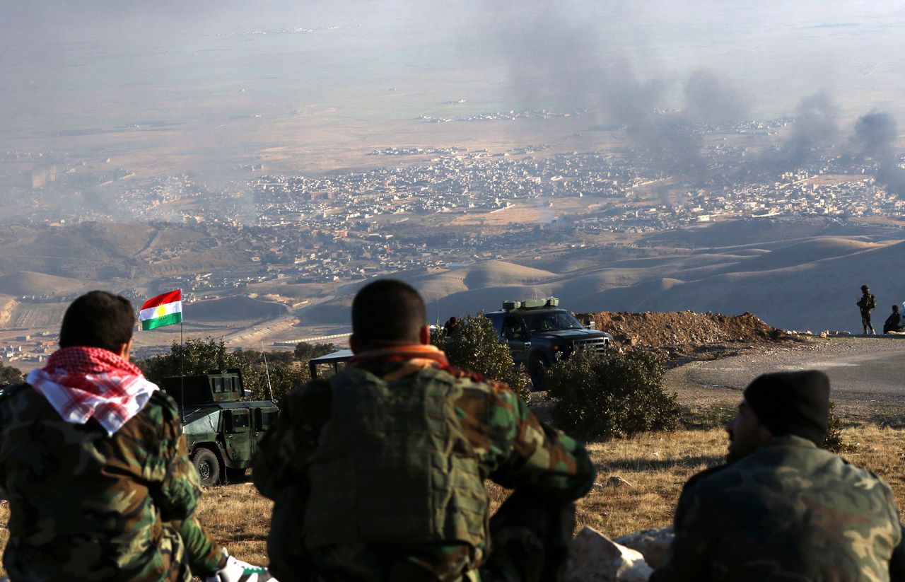 Koerdische strijders kijken naar de rook boven Sinjar.
