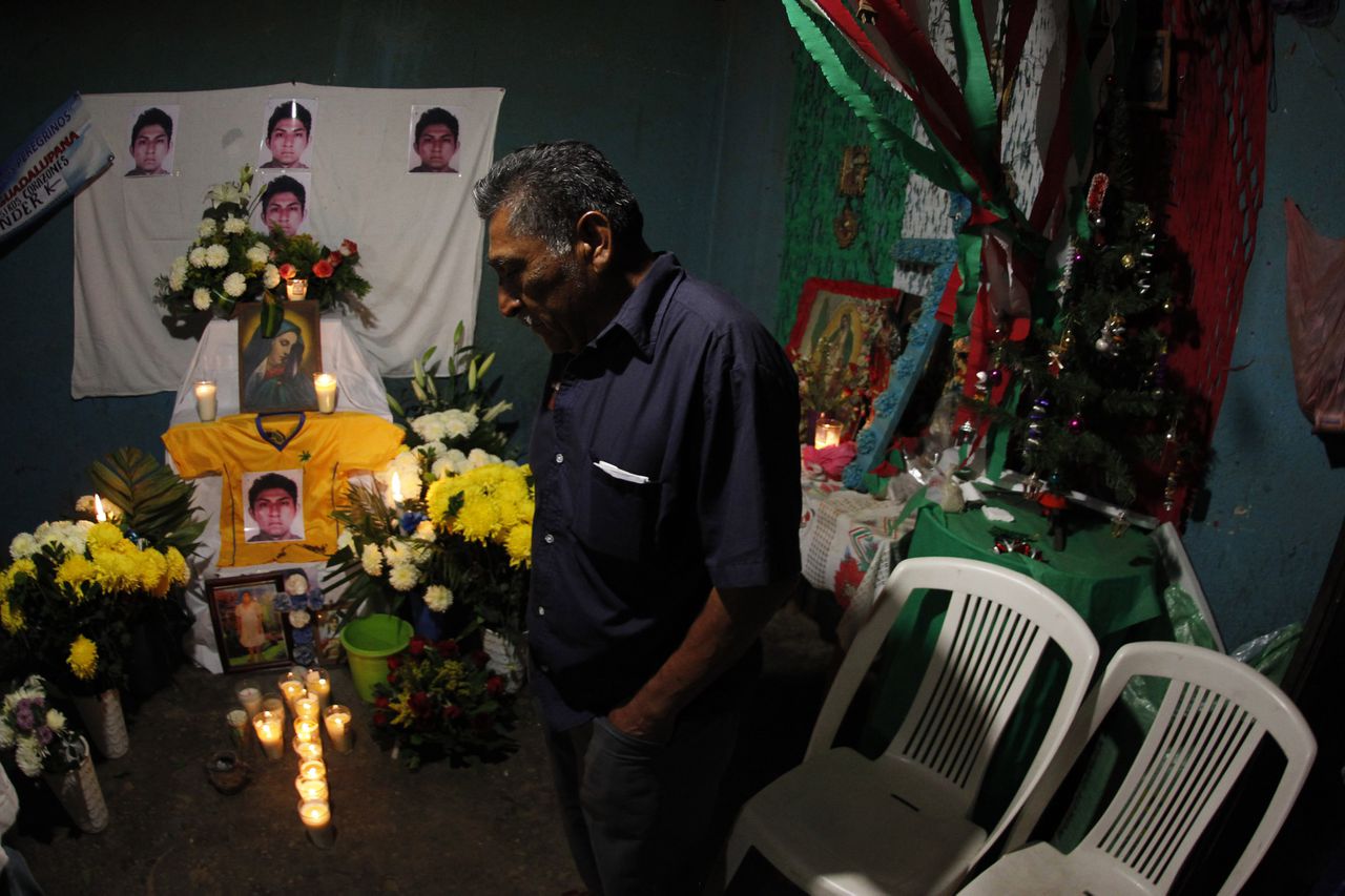 Ezequiel Mora, de vader van Alexander Mora, staat thuis voor een altaar met foto's van zijn zoon.