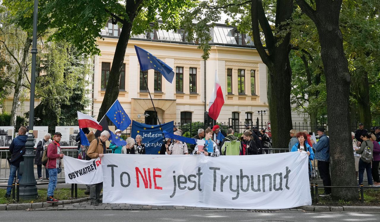 Poolse pro-EU-activisten bij het constitutioneel hof met EU-vlaggen en een spandoek waarop staat: ‘dit is geen gerechtshof’