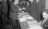 Minister Ko Suurhoff (r) reikt in 1957 het eerste ouderdomspensioen uit aan A. Bakker, een dan 70-jarige oud-belastingambtenaar. Foto Joop van Bilsen/National Archief 