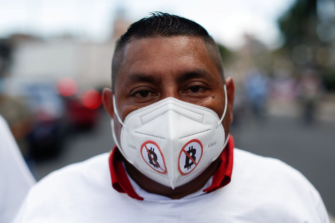 Een inwoner van El Salvador met een mondkapje tegen de invoering van de bitcoin.