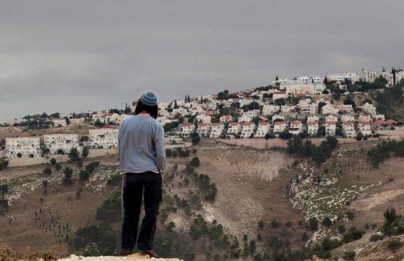 Een Joodse kolonist kijkt naar de nederzetting Maaleh Adumim op de bezette Westelijke Jordaanoever.